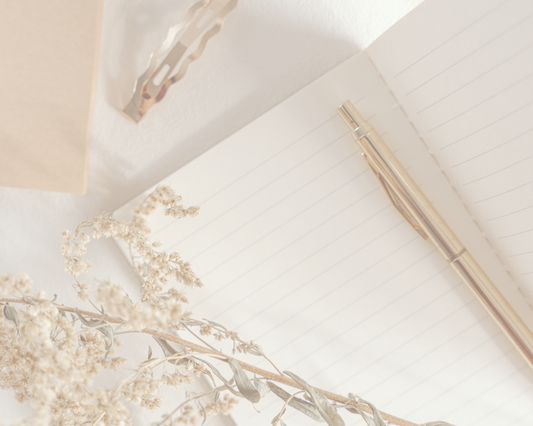 Carnet ouvert avec un stylo doré et des fleurs séchées sur fond beige, pour un article sur les prénoms populaires au Québec