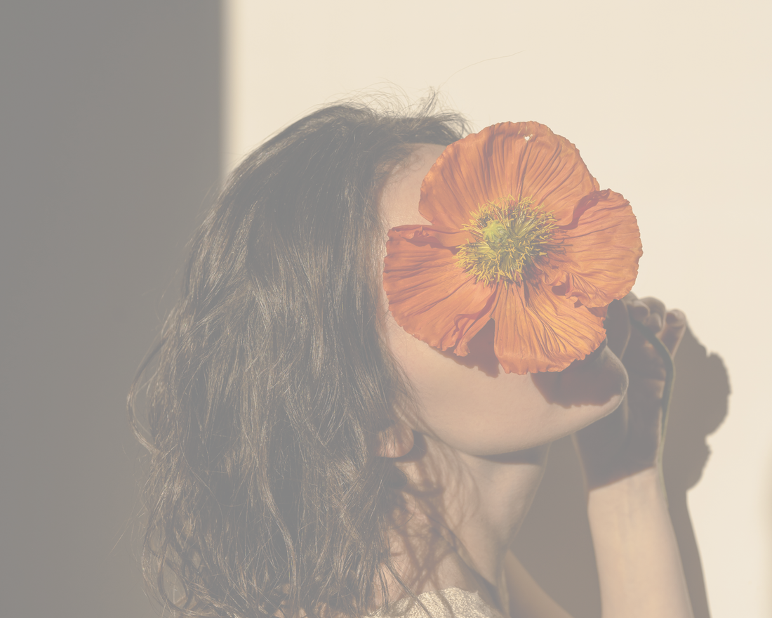 Femme aux cheveux bruns ondulés qui tient un coquelicot orange devant son visage, pour un article sur la durée des prénoms dans le top 10 au Québec