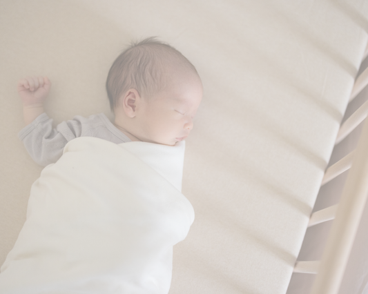Nouveau-né endormi dans son lit, emmailloté dans une couverture blanche