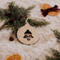 Boule de Noël personnalisée - Découpe : cloche ajourée avec cœur central, entourée de sapin et d’oranges séchées.