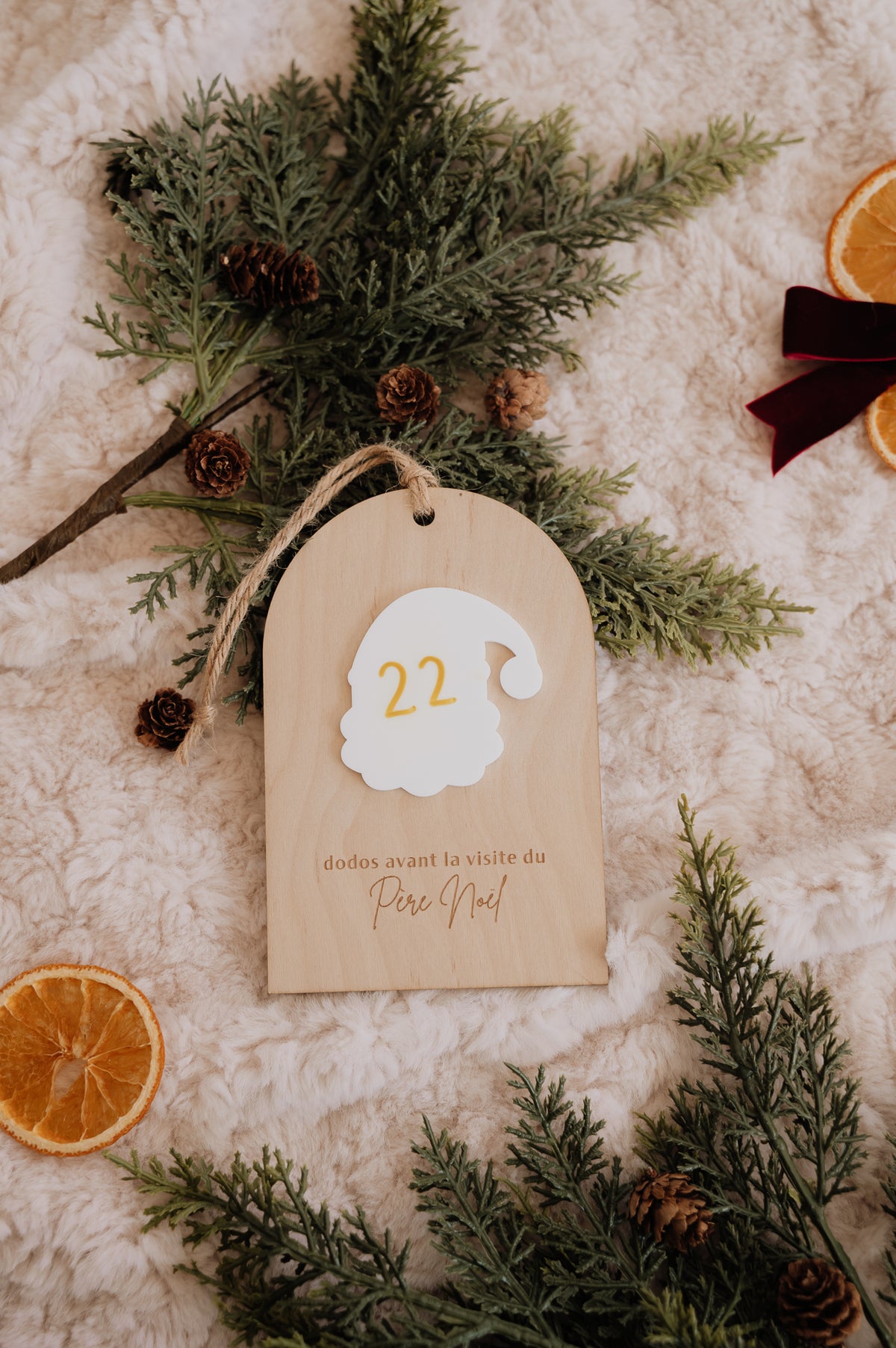 Dodos avant Noël : décompte en bois avec le nombre 22 sur le Père Noël blanc, entouré de sapin et d’oranges séchées.