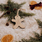 Ornement personnalisé - Pain d’épice : bonhomme en bois gravé Olivia, sur une couverture crème avec sapin et oranges.