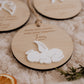 Boule de Noël personnalisée - Superposée : vue rapprochée du bébé ange blanc avec aile et auréole, sur fond de bois.