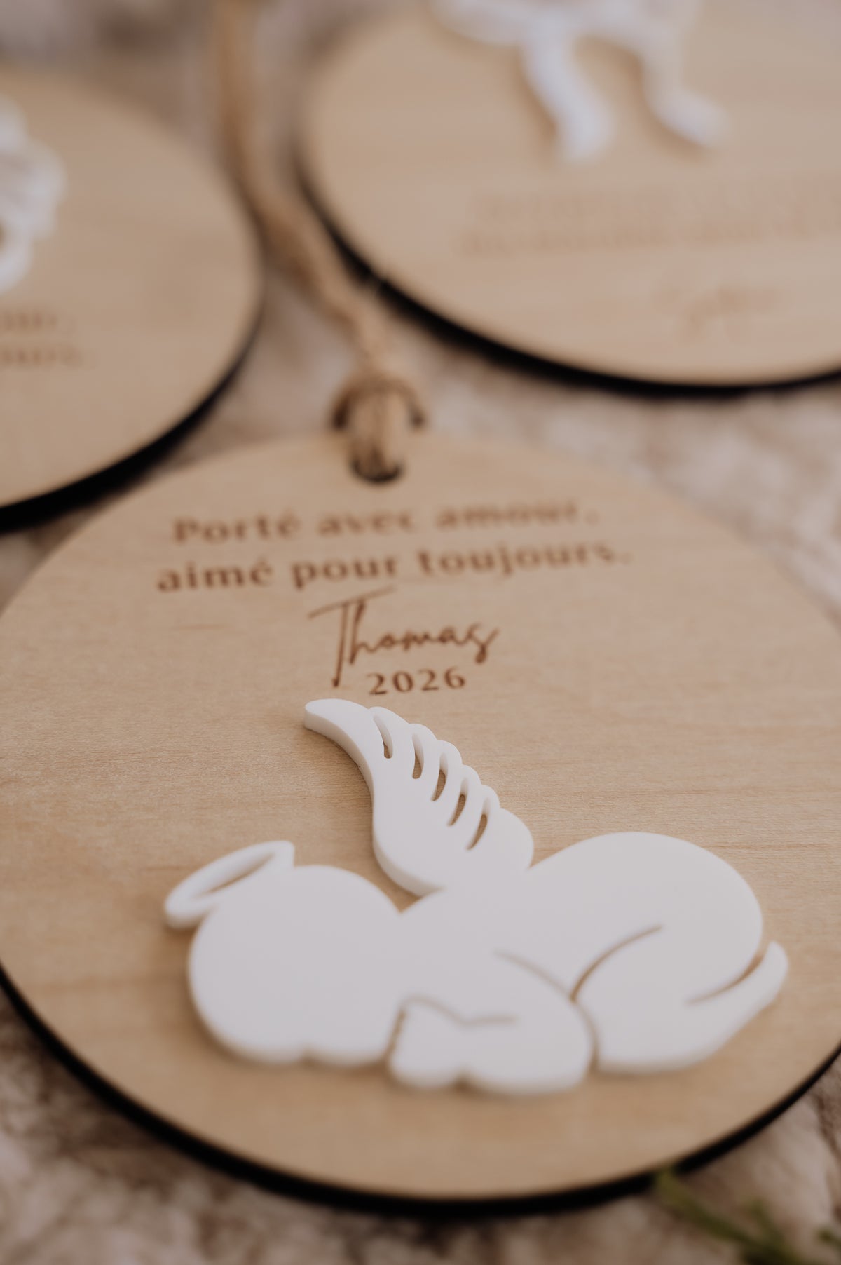 Boule de Noël personnalisée - Superposée : gros plan du bébé ange blanc et de l’inscription « Thomas 2026 ».