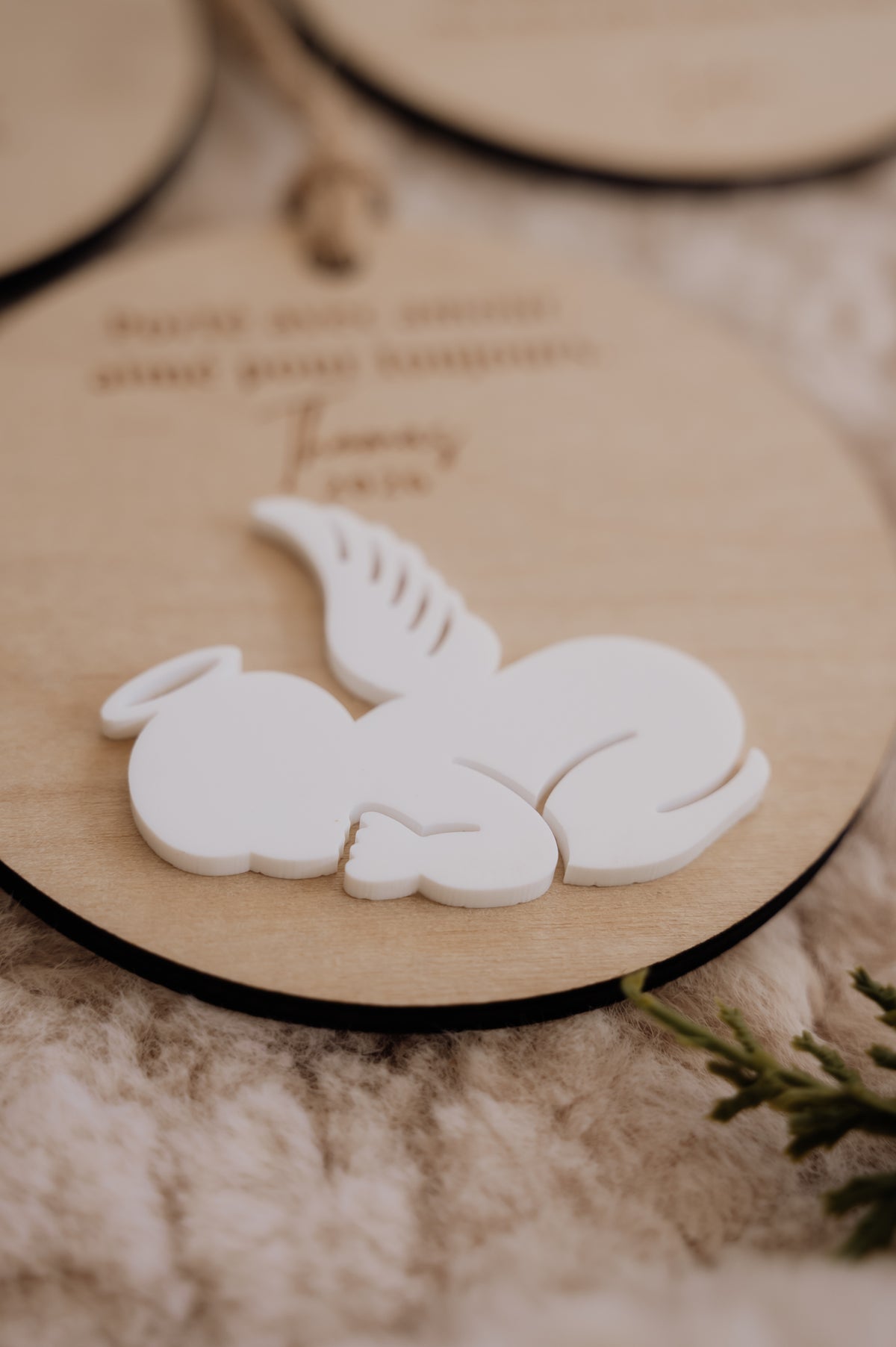 Boule de Noël personnalisée - Superposée : détail du bébé ange blanc couché, montrant le relief sur le disque en bois.