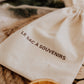 Le Sac à souvenirs : gros plan du sac en coton imprimé, sur un plateau tressé avec une tranche d’orange séchée.