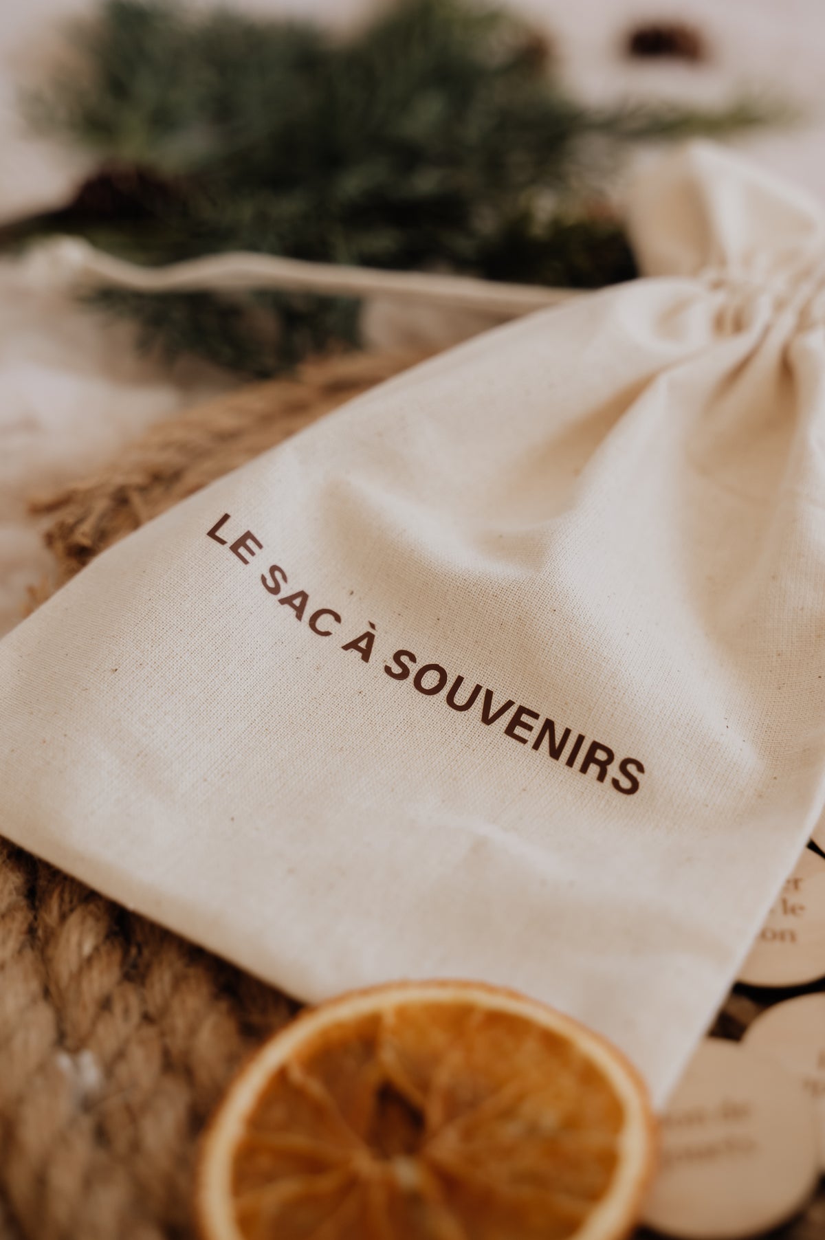 Le Sac à souvenirs : gros plan du sac en coton imprimé, sur un plateau tressé avec une tranche d’orange séchée.