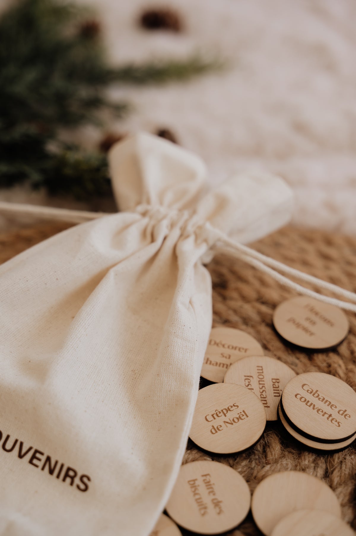 Le Sac à souvenirs : sac à cordons près des pastilles en bois « Crêpes de Noël » et « Cabane de couvertes ».