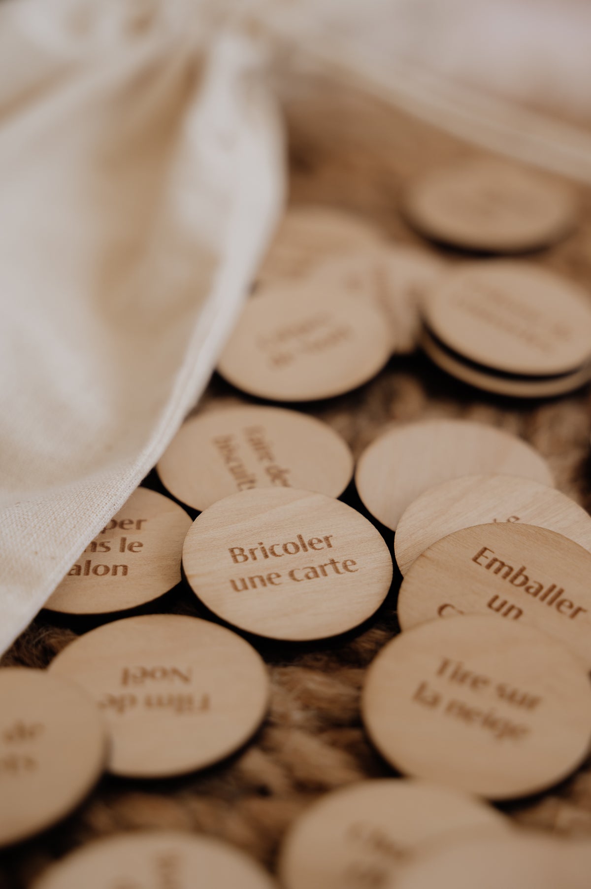 Le Sac à souvenirs : gros plan de pastilles en bois, dont Bricoler une carte, près du sac en coton.