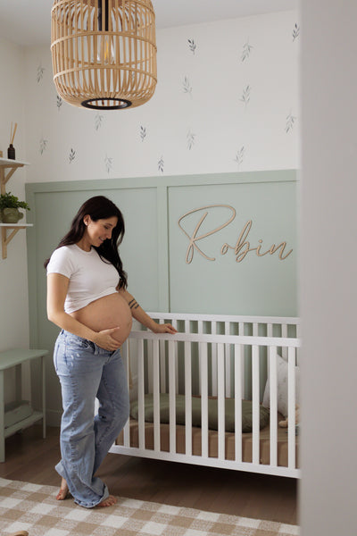 Nom en bois personnalisé Robin en lettres attachées au-dessus d’un lit de bébé blanc.